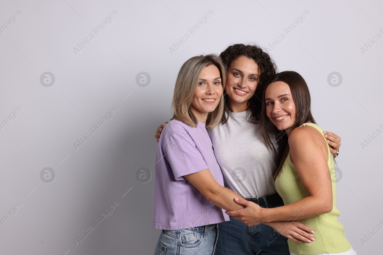 Portrait of happy friends hugging on grey background. Space for text Photo of Portrait of happy friends hugging on grey background. Space for text