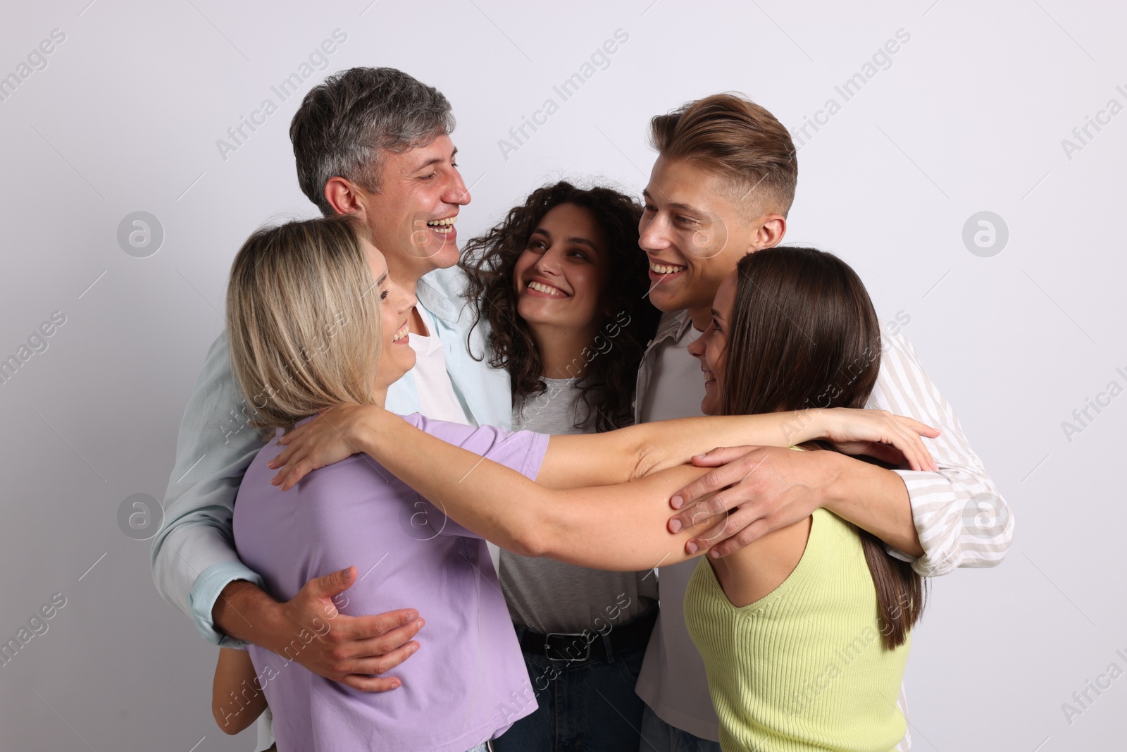 Group of happy friends hugging on grey background Photo of Group of happy friends hugging on grey background