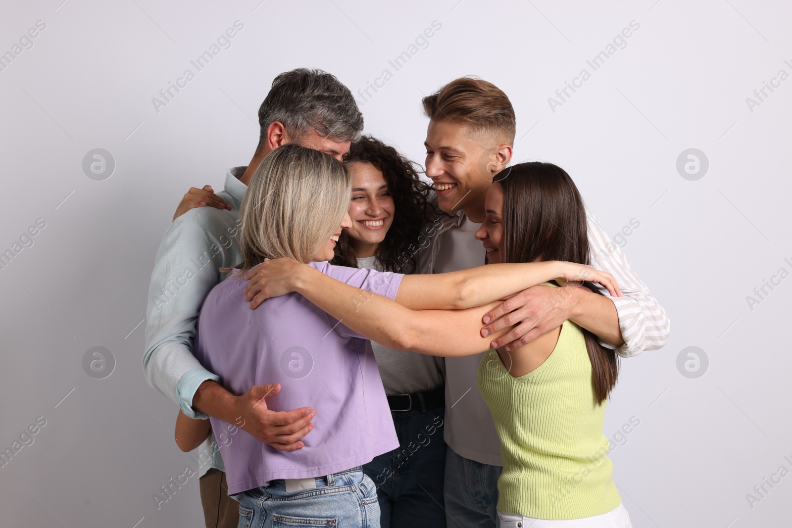 Group of happy friends hugging on grey background Photo of Group of happy friends hugging on grey background