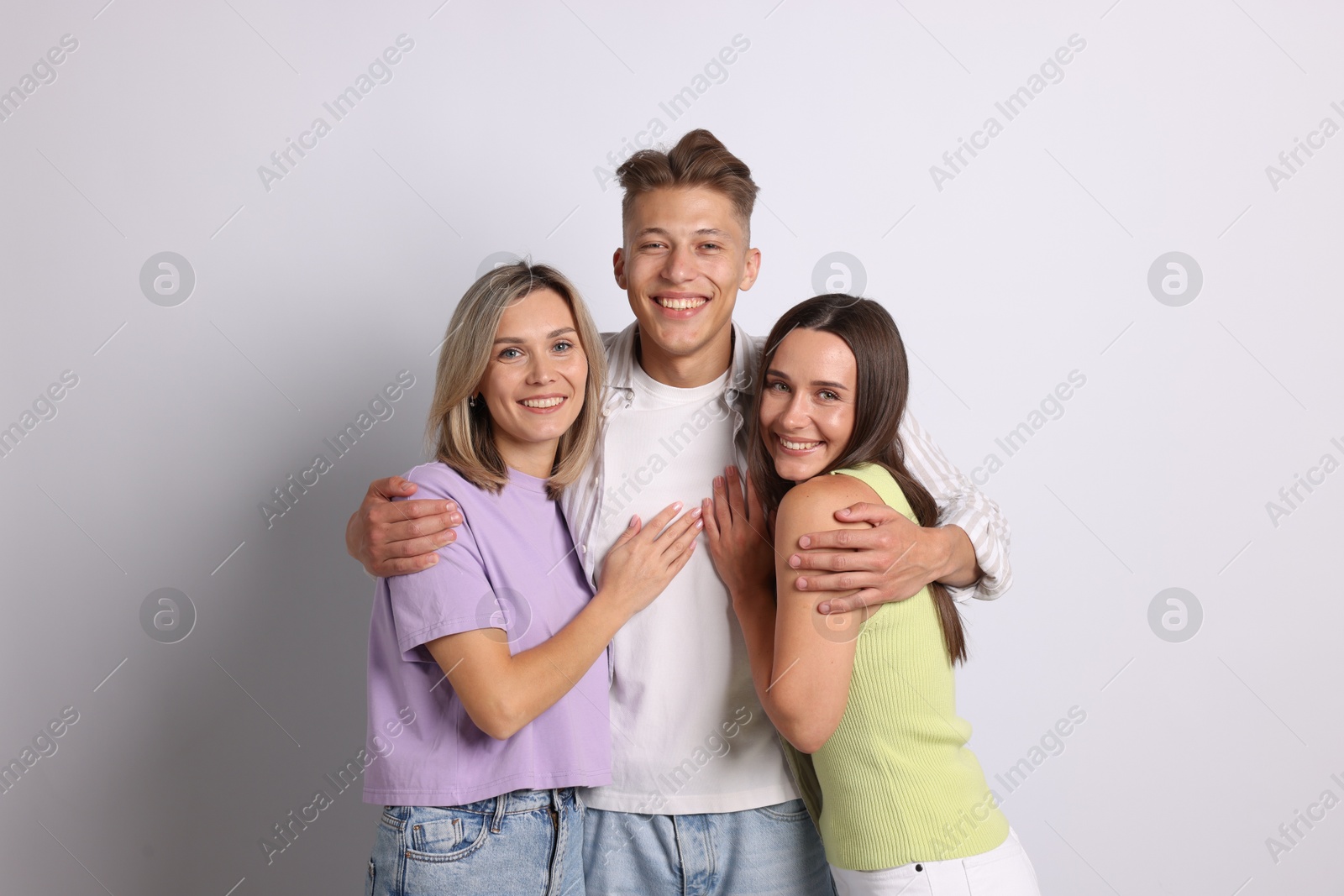 Portrait of happy friends hugging on grey background Photo of Portrait of happy friends hugging on grey background