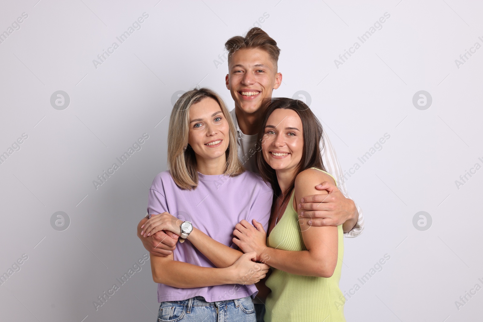 Portrait of happy friends hugging on grey background Photo of Portrait of happy friends hugging on grey background