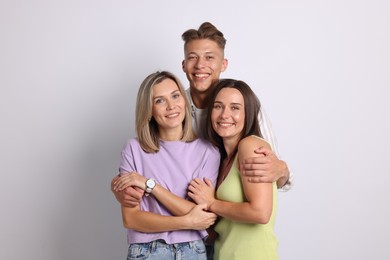 Photo of Portrait of happy friends hugging on grey background