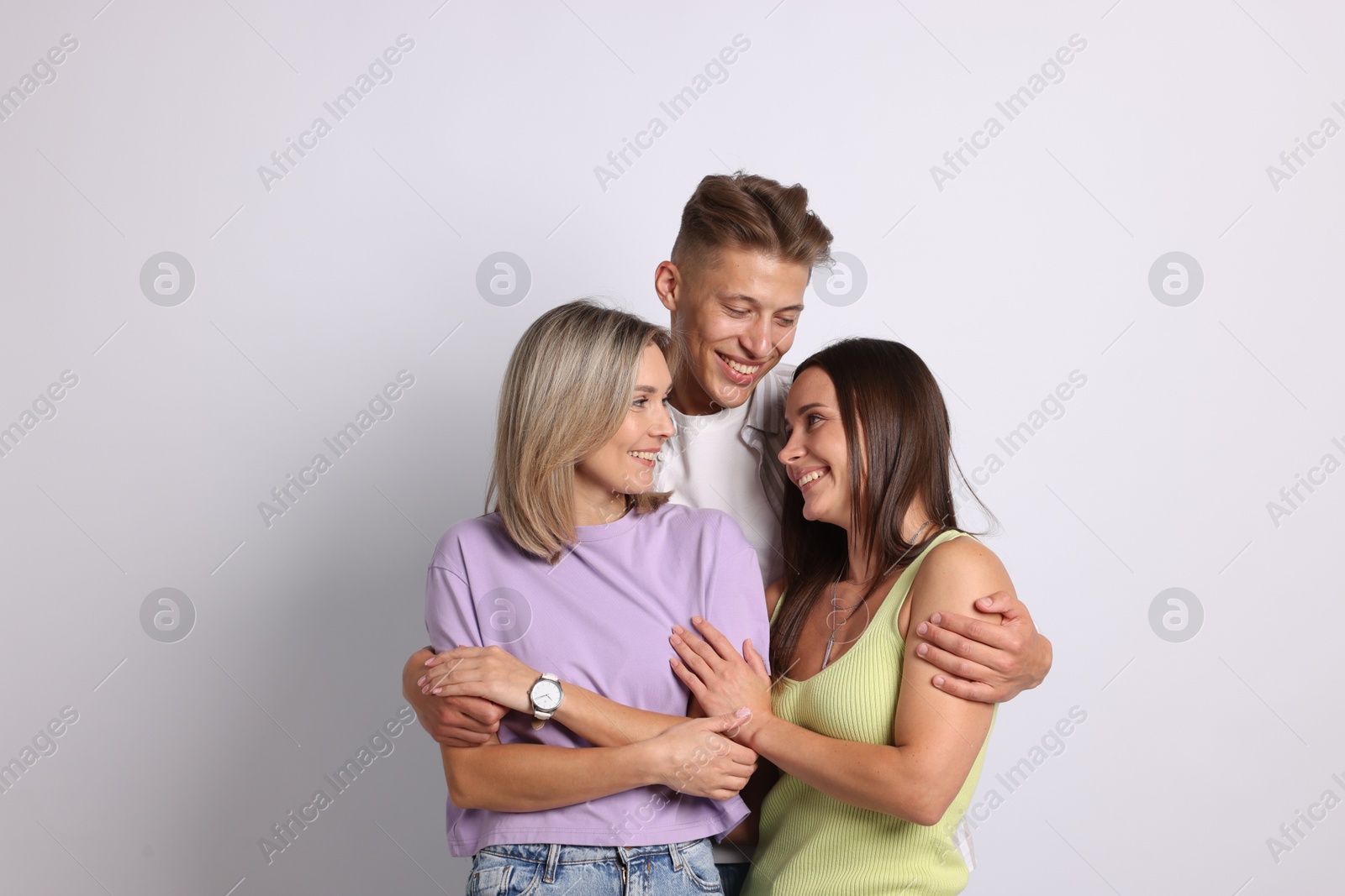 Happy friends hugging each other on grey background Photo of Happy friends hugging each other on grey background