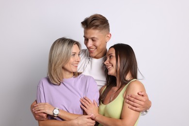 Photo of Happy friends hugging each other on grey background