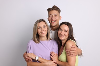 Photo of Portrait of happy friends hugging on grey background