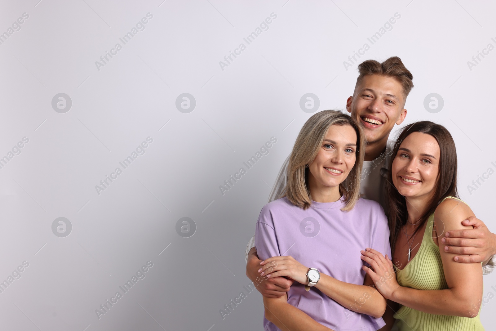 Portrait of happy friends hugging on grey background. Space for text Photo of Portrait of happy friends hugging on grey background. Space for text