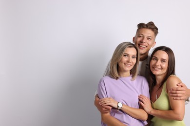 Photo of Portrait of happy friends hugging on grey background. Space for text