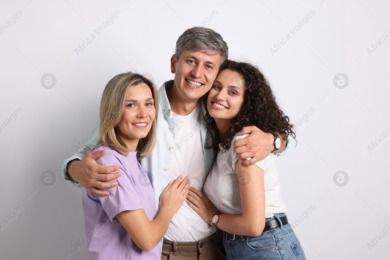 Photo of Portrait of happy friends hugging on grey background