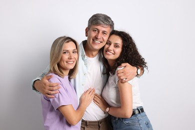 Photo of Portrait of happy friends hugging on grey background