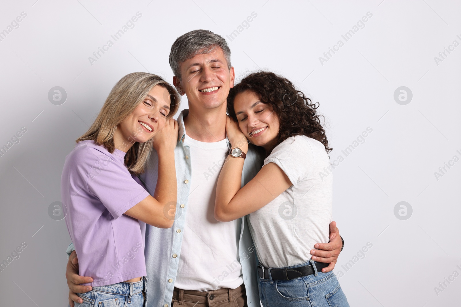 Photo of Happy friends hugging each other on grey background