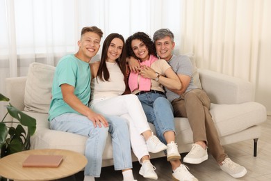 Photo of Happy friends hugging and having fun on sofa at home