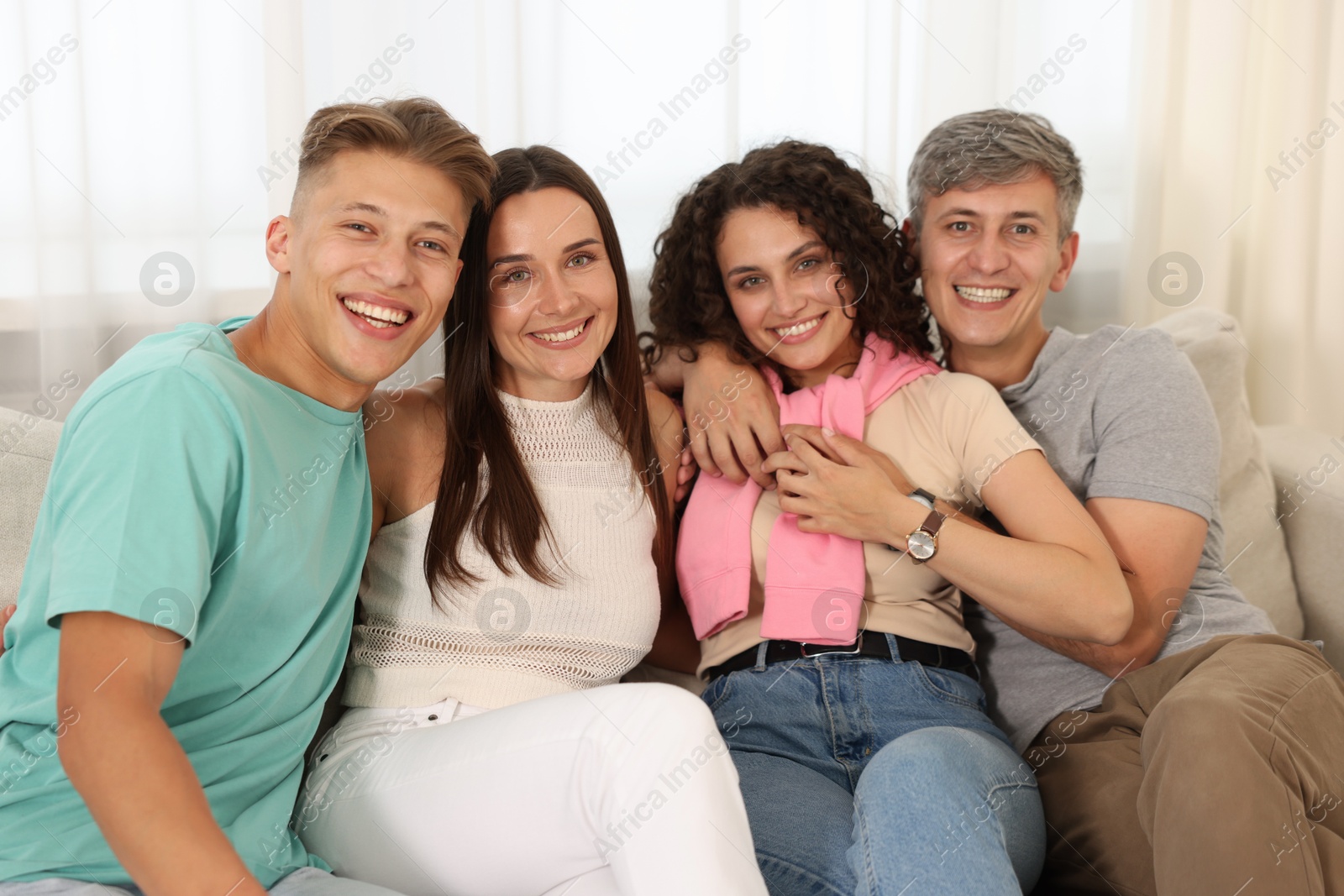 Photo of Happy friends hugging and having fun on sofa at home