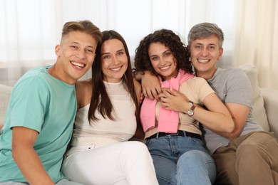 Photo of Happy friends hugging and having fun on sofa at home