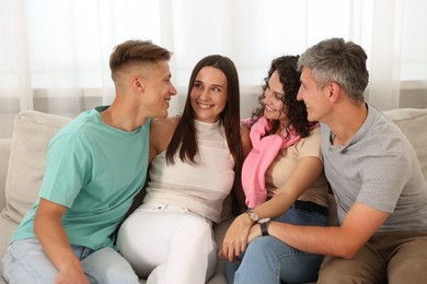 Photo of Happy friends hugging and having fun on sofa at home