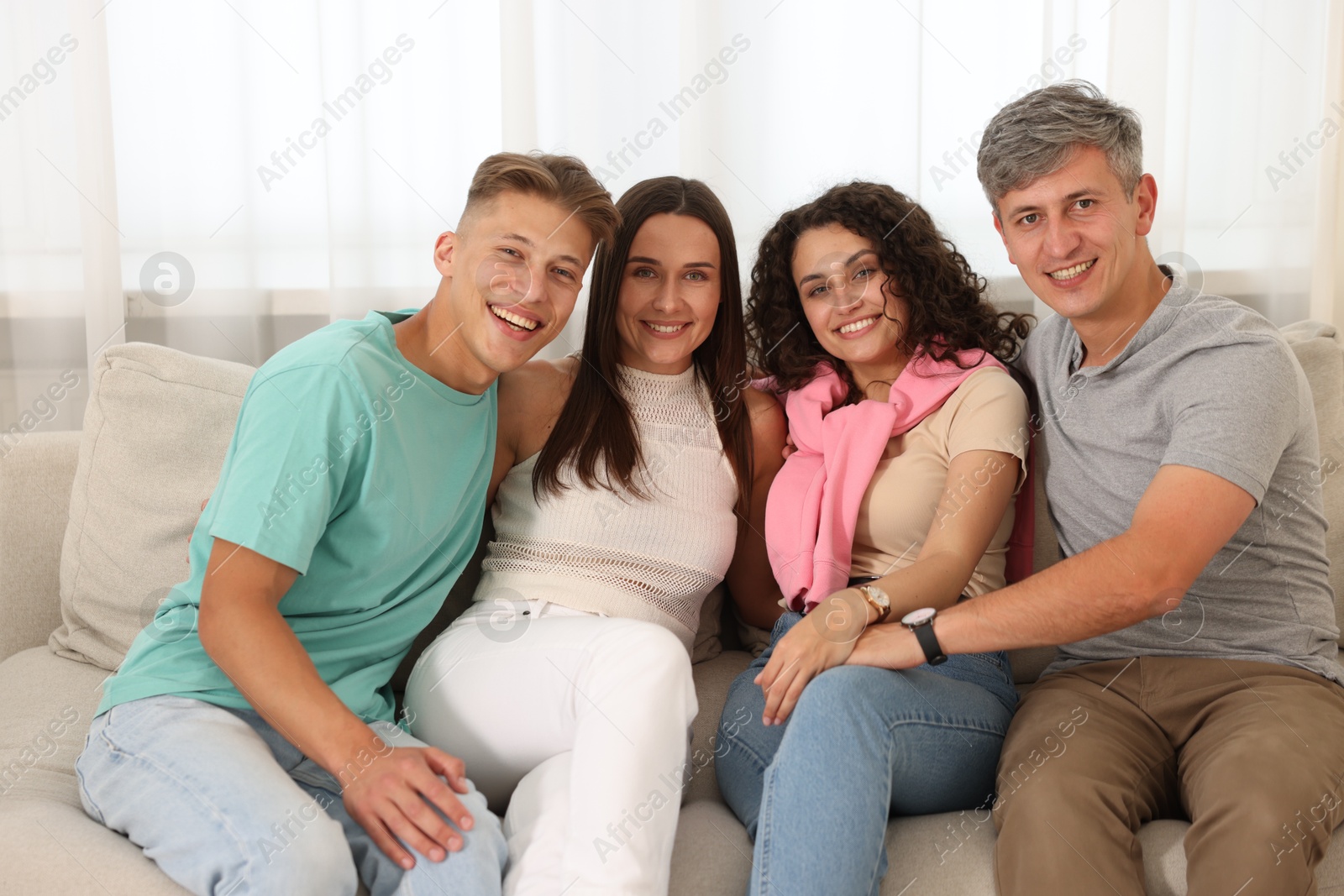 Photo of Happy friends hugging and having fun on sofa at home