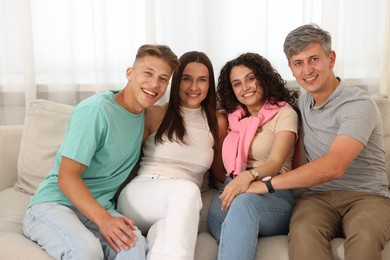 Photo of Happy friends hugging and having fun on sofa at home