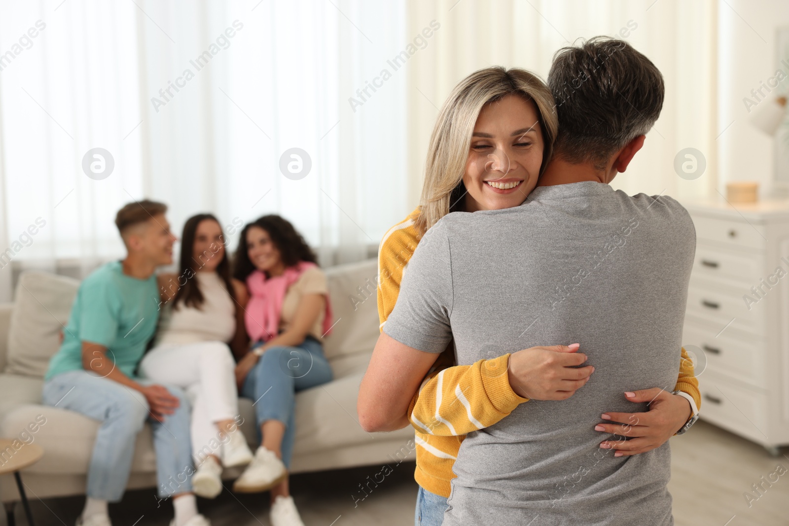 Photo of Happy friends hugging at home, selective focus