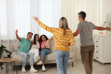 Photo of Happy friends greeting couple on sofa at home