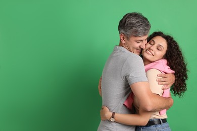 Photo of Happy friends hugging each other on green background. Space for text