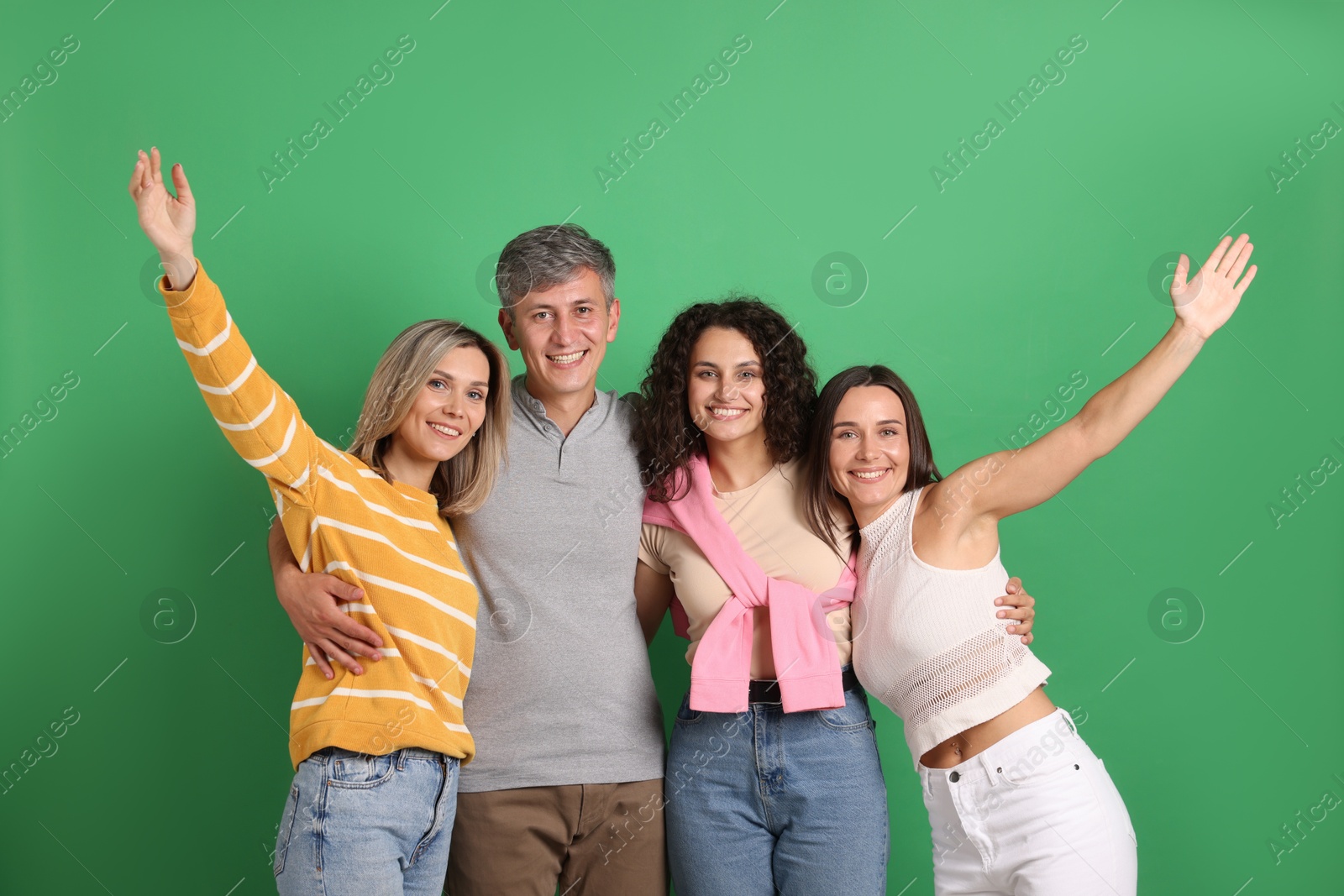 Photo of Happy friends hugging each other on green background