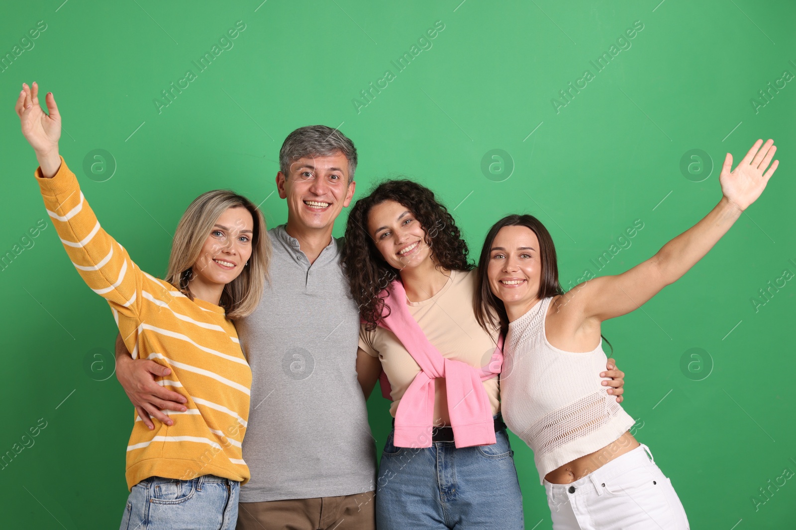 Photo of Happy friends hugging each other on green background
