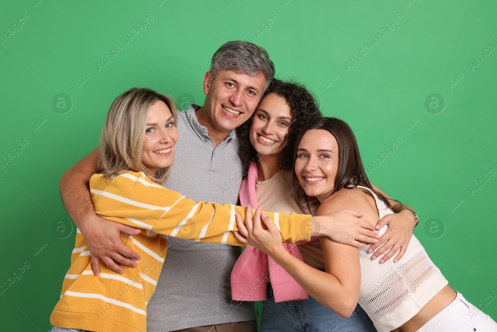 Photo of Happy friends hugging each other on green background