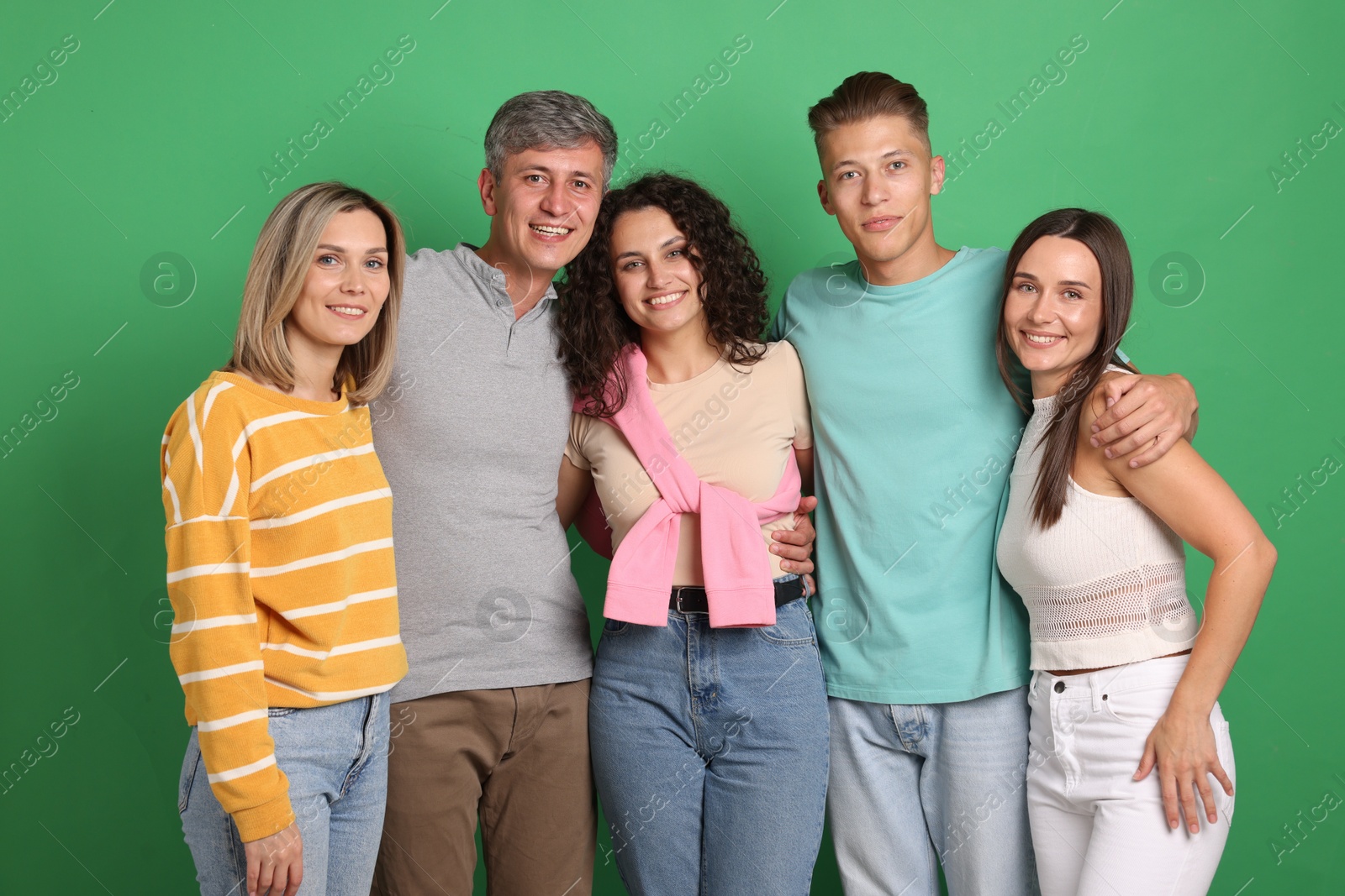 Photo of Happy friends hugging each other on green background