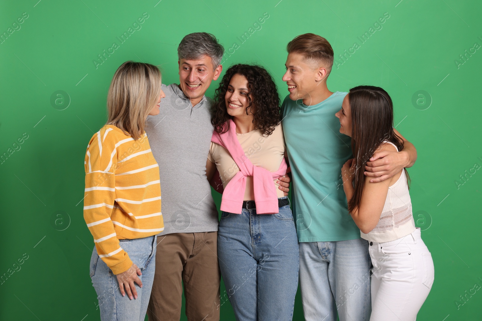 Photo of Happy friends hugging each other on green background
