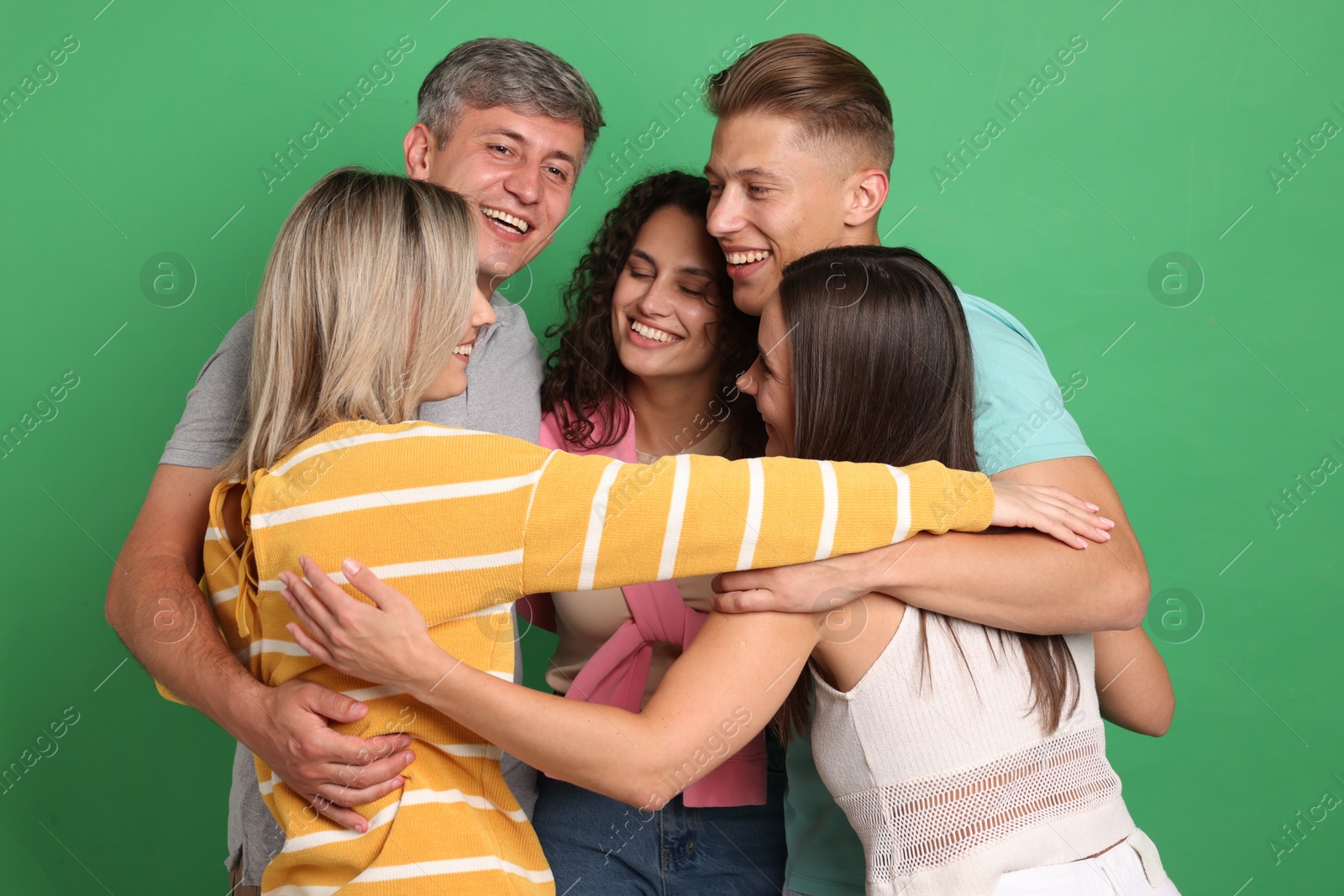Photo of Happy friends hugging each other on green background