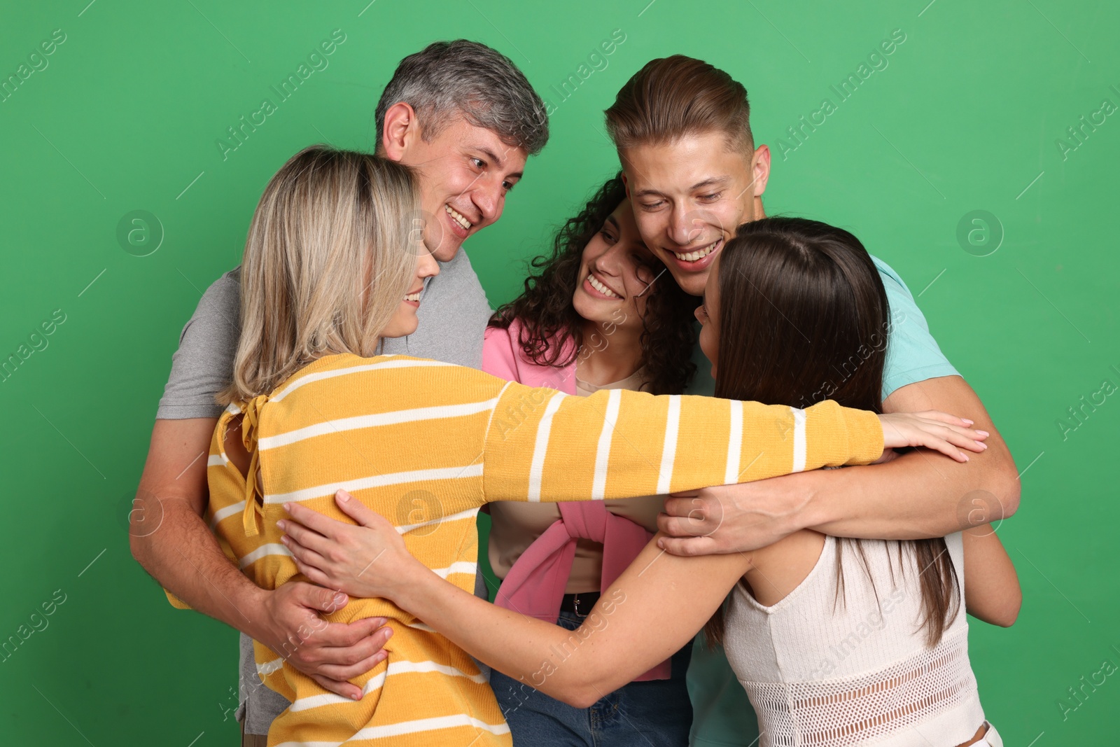 Photo of Happy friends hugging each other on green background