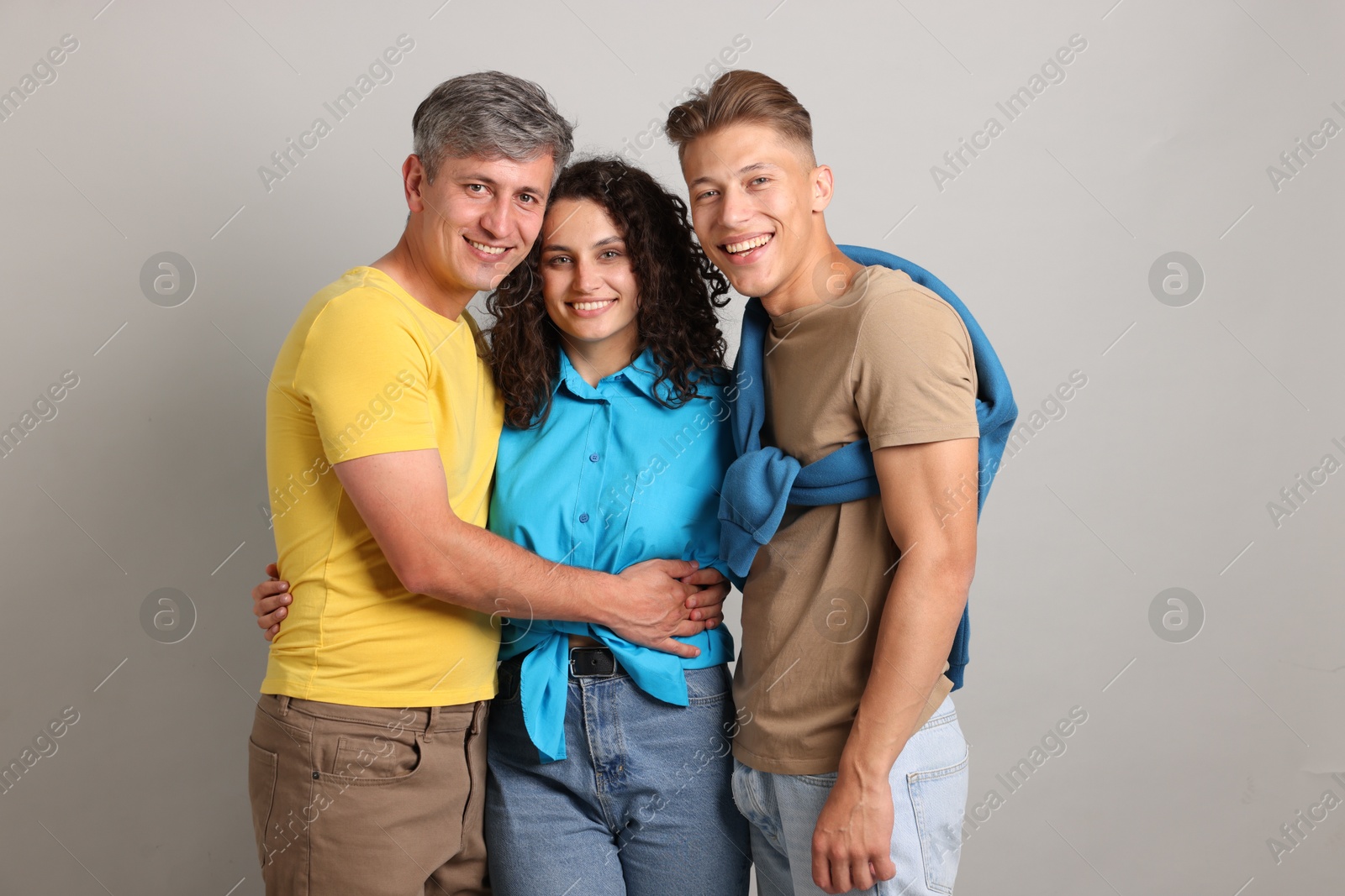 Photo of Happy friends hugging each other on grey background