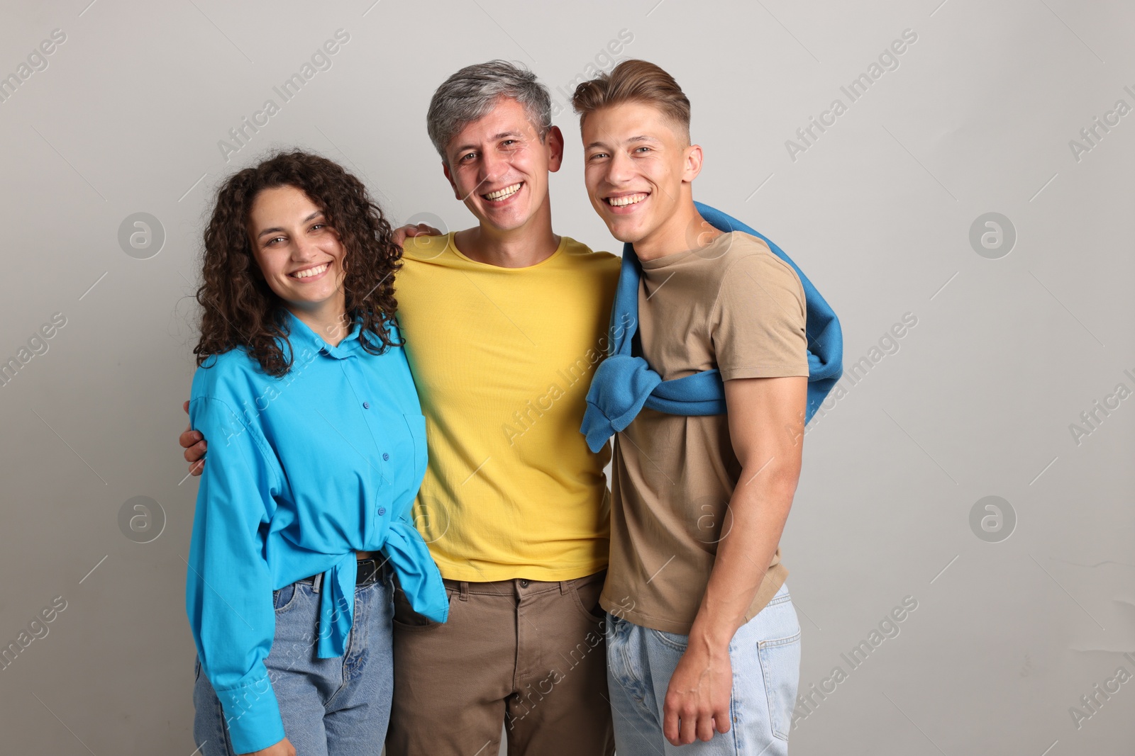 Photo of Happy friends hugging each other on grey background