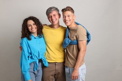 Photo of Happy friends hugging each other on grey background
