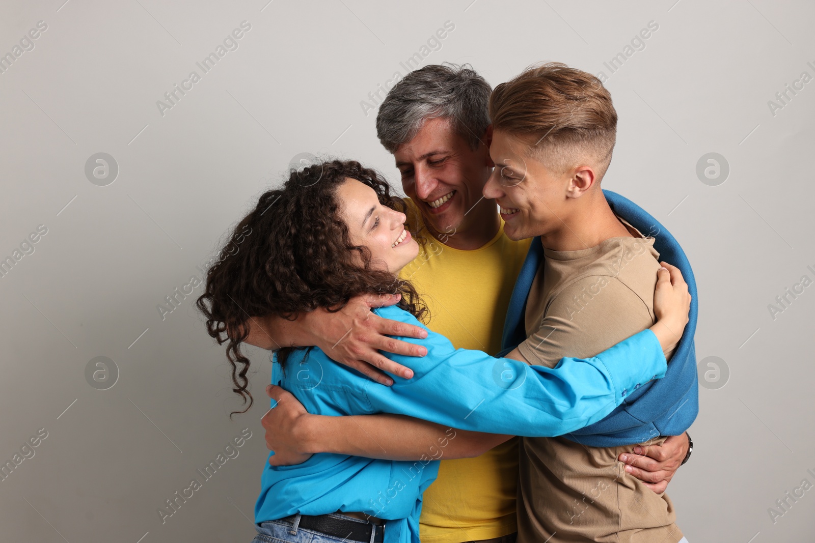 Photo of Happy friends hugging each other on grey background