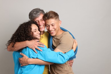 Photo of Happy friends hugging each other on grey background