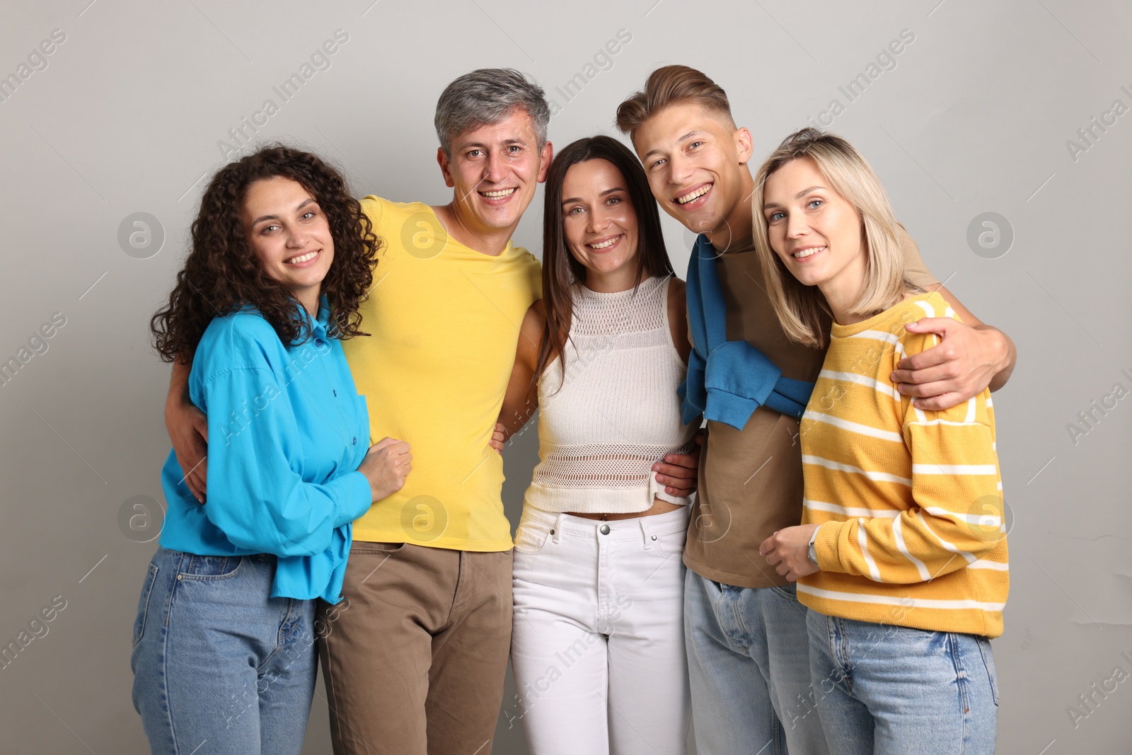 Photo of Group of happy friends hugging on grey background