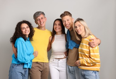 Photo of Group of happy friends hugging on grey background