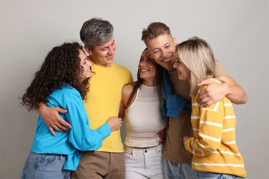 Photo of Group of happy friends hugging on grey background