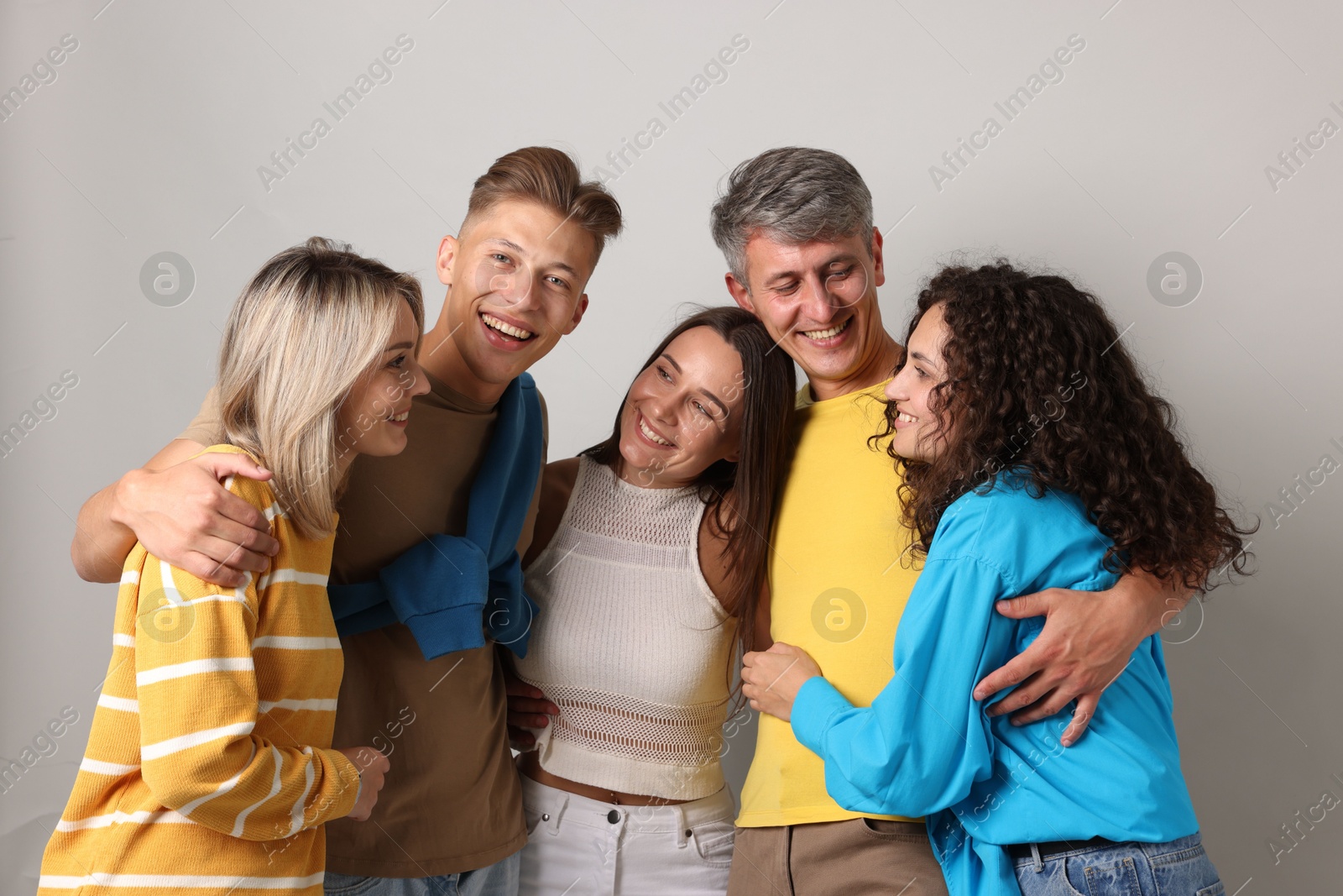 Group of happy friends hugging on grey background Photo of Group of happy friends hugging on grey background