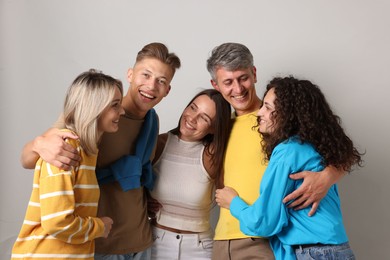 Photo of Group of happy friends hugging on grey background
