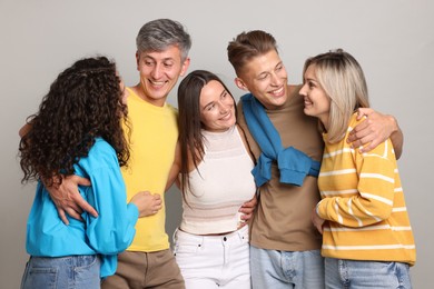 Photo of Group of happy friends hugging on grey background