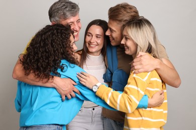 Photo of Group of happy friends hugging on grey background