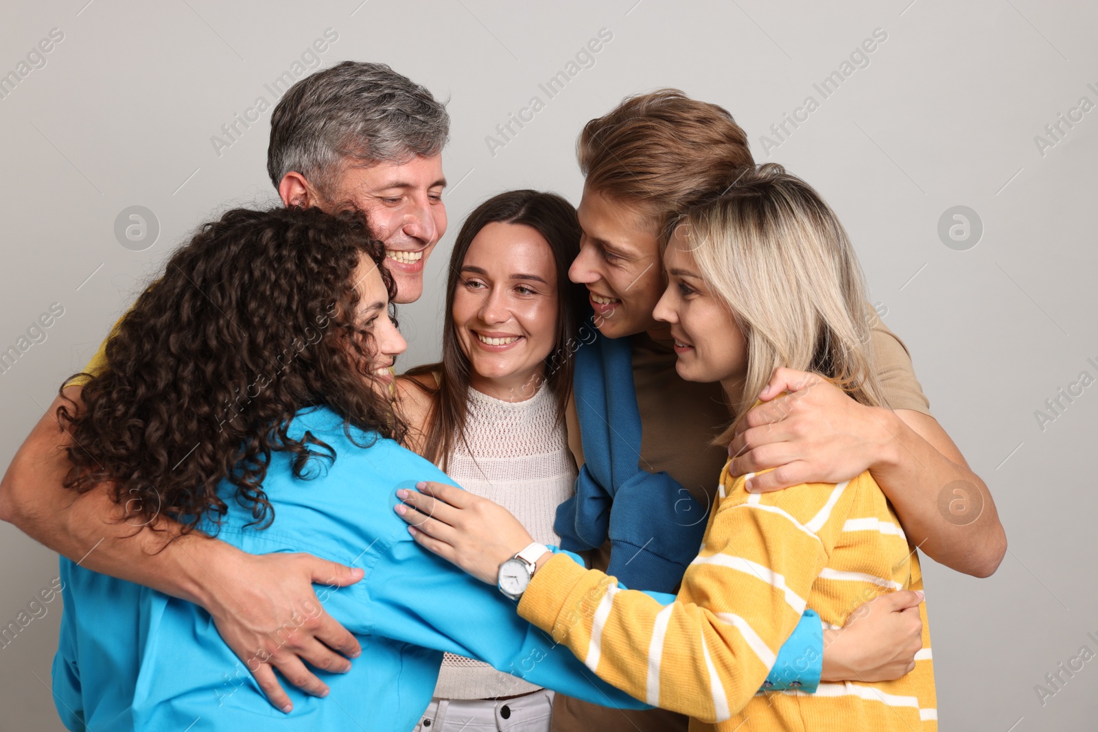Group of happy friends hugging on grey background Photo of Group of happy friends hugging on grey background