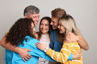 Photo of Group of happy friends hugging on grey background