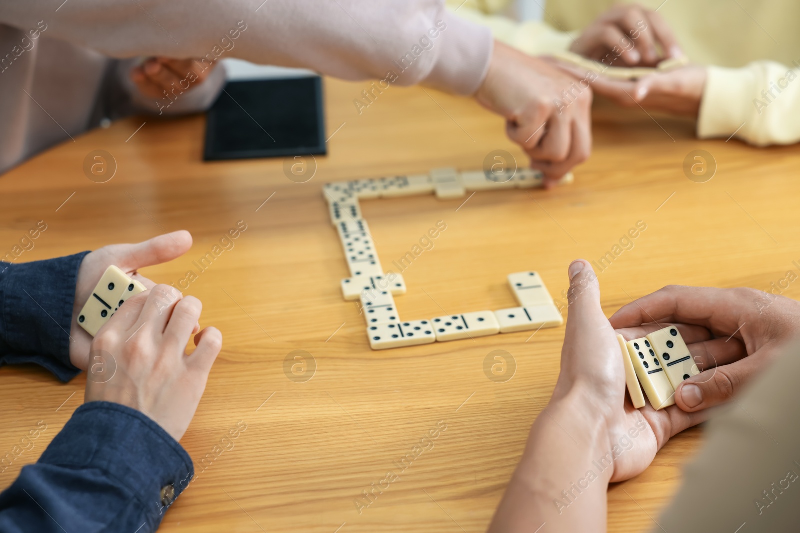 Friends playing dominoes at wooden table, closeup Photo of Friends playing dominoes at wooden table, closeup