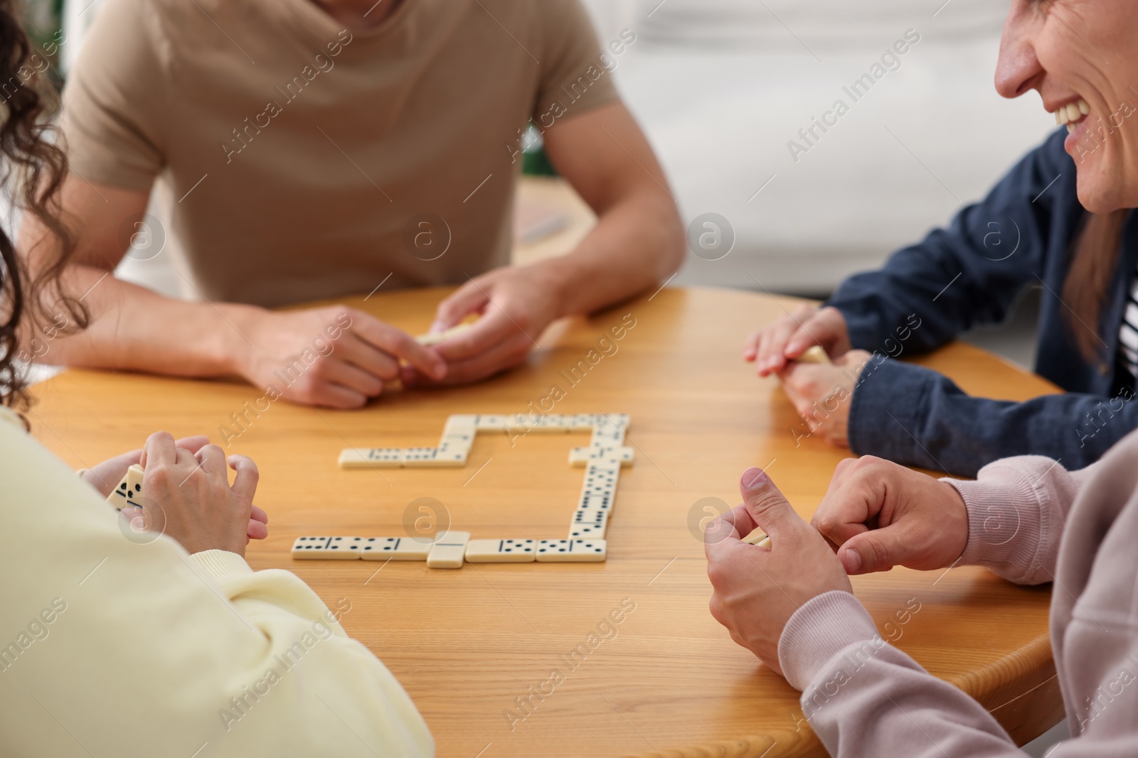 Friends playing dominoes at wooden table indoors, closeup Photo of Friends playing dominoes at wooden table indoors, closeup