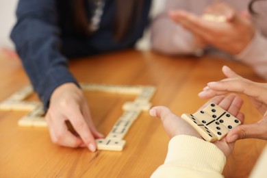 Photo of Friends playing dominoes at wooden table, closeup