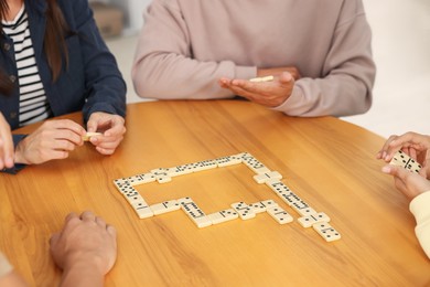 Photo of Friends playing dominoes at wooden table, closeup
