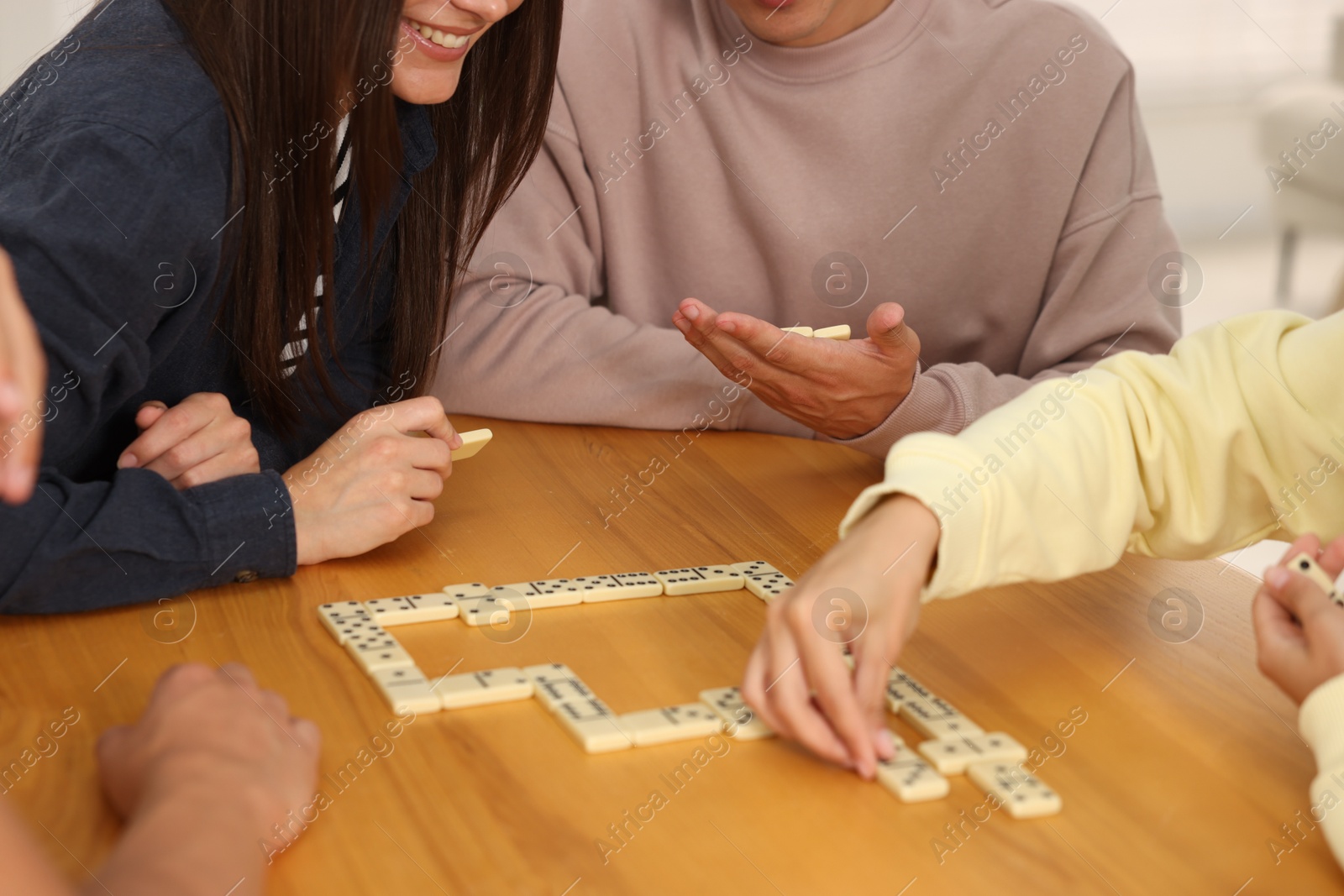 Friends playing dominoes at wooden table, closeup Photo of Friends playing dominoes at wooden table, closeup