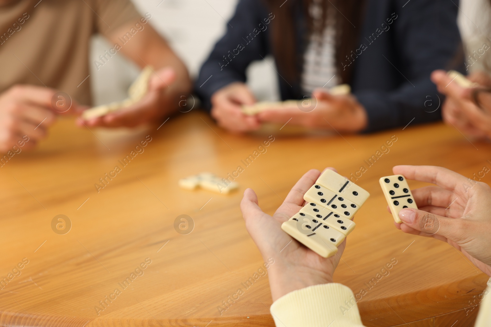 Friends playing dominoes at wooden table, closeup Photo of Friends playing dominoes at wooden table, closeup